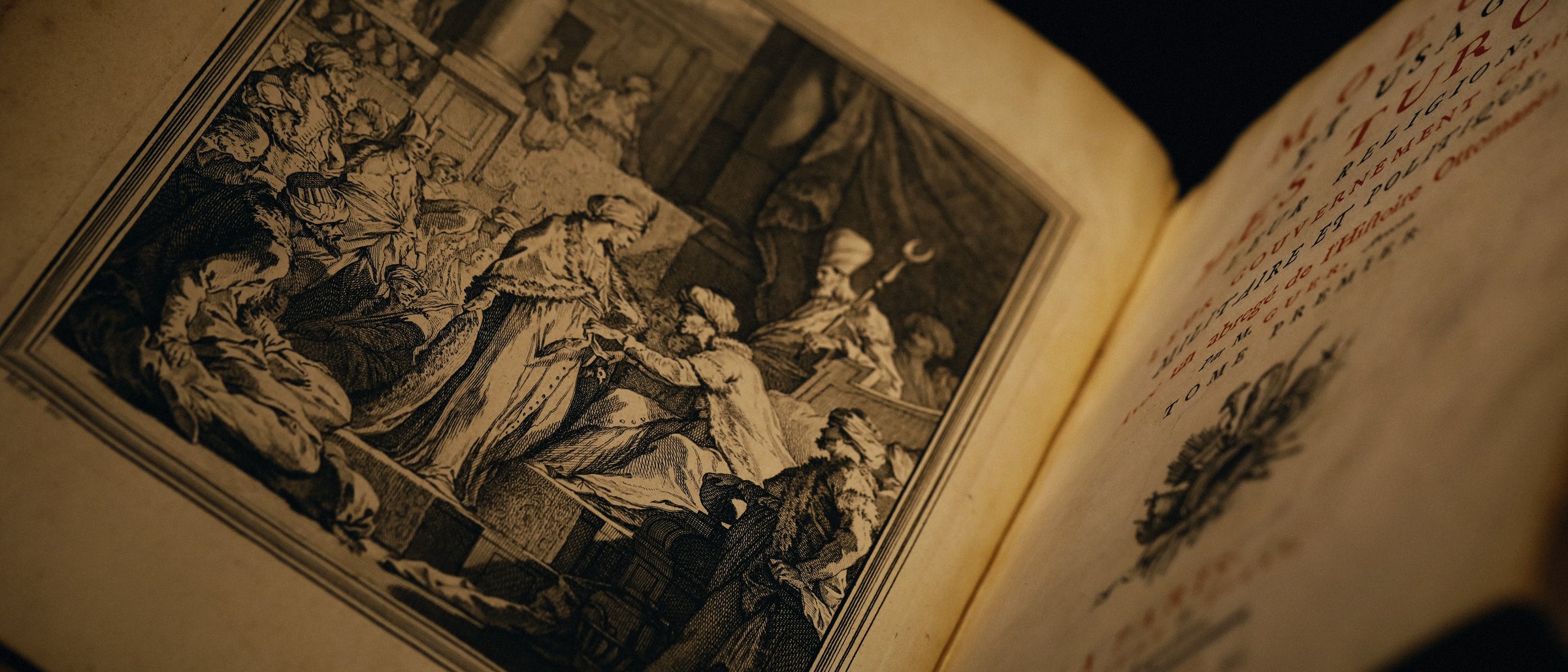 Open antique book with an engraving, lit warmly